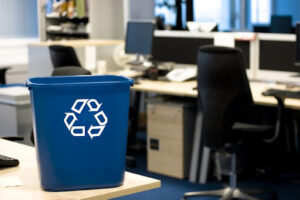 An essential part of creating a recycling-friendly workplace is making it so easy to recycle that employees have no reason not to do their part. Here is a blue recycling bin in an office.