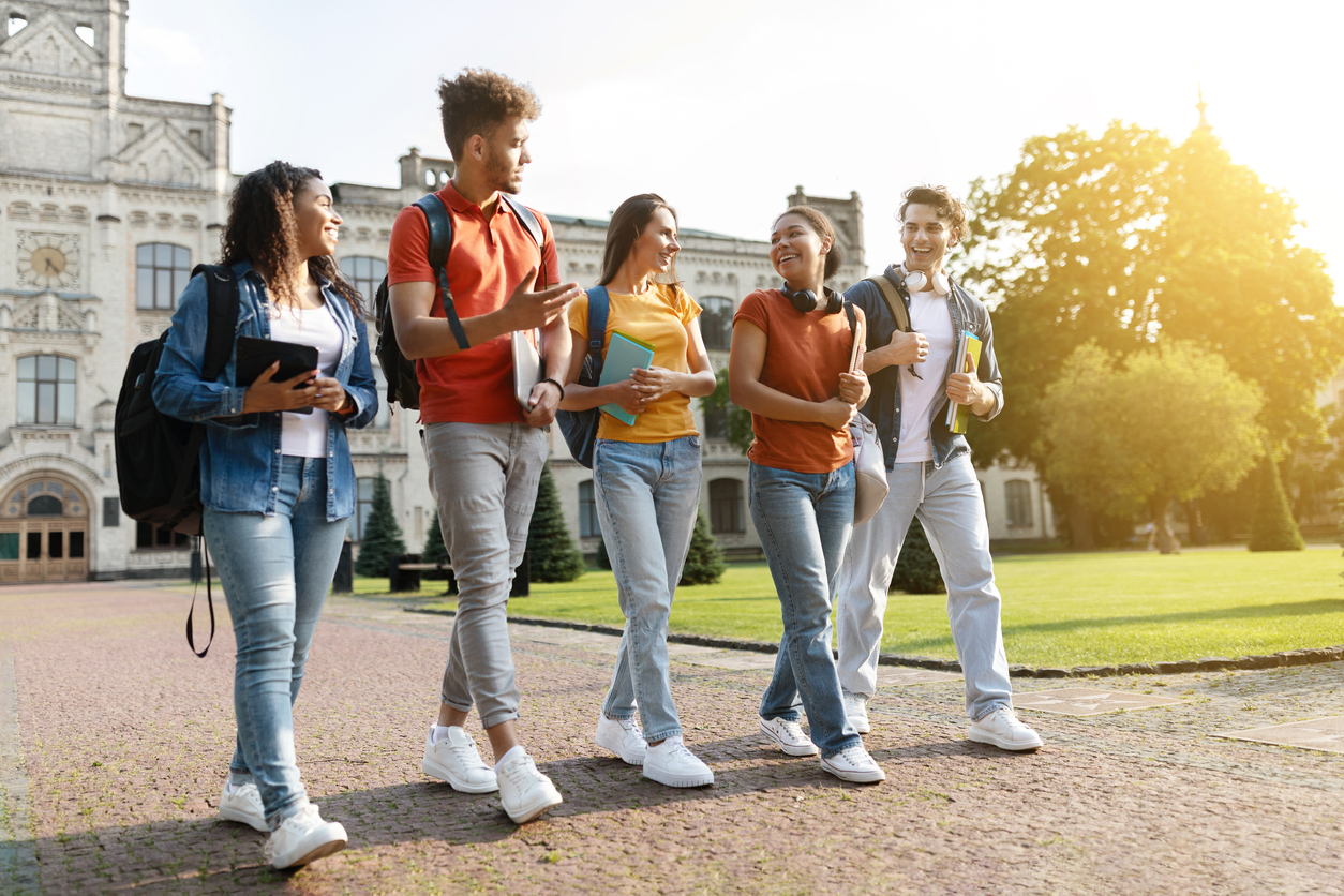 group of happy young people with books and backpacks going to classes. University recycling strategies.